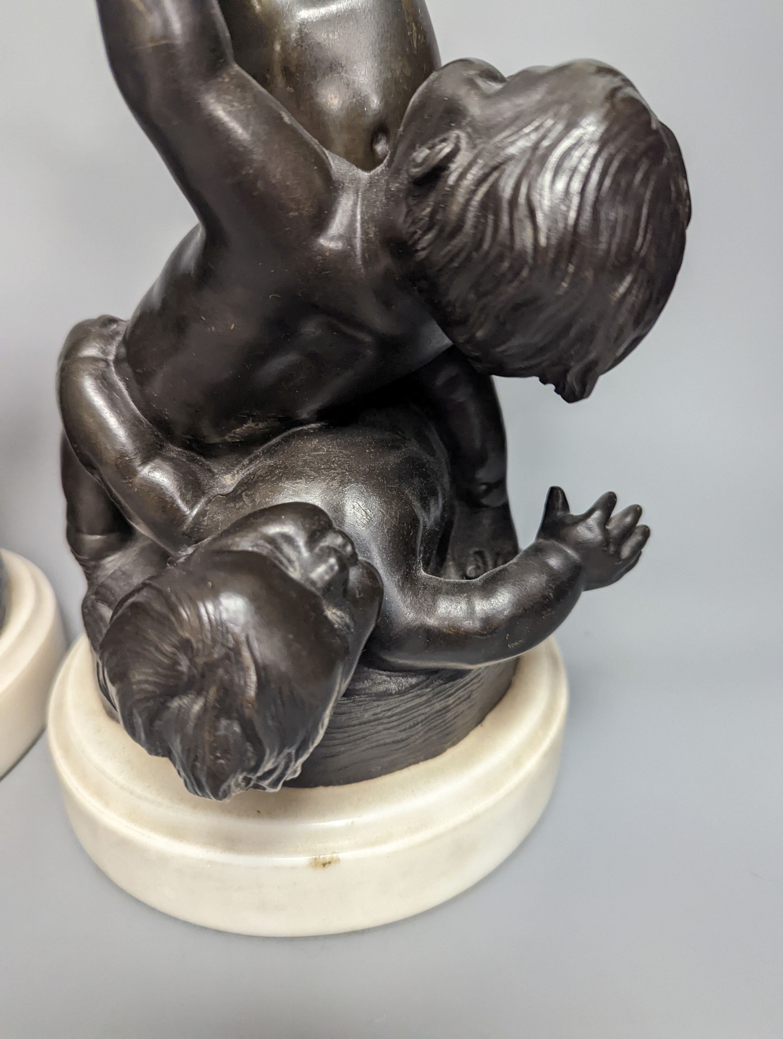 A pair of bronze figure groups, trio of putto, on white marble plinths, tallest 26cm